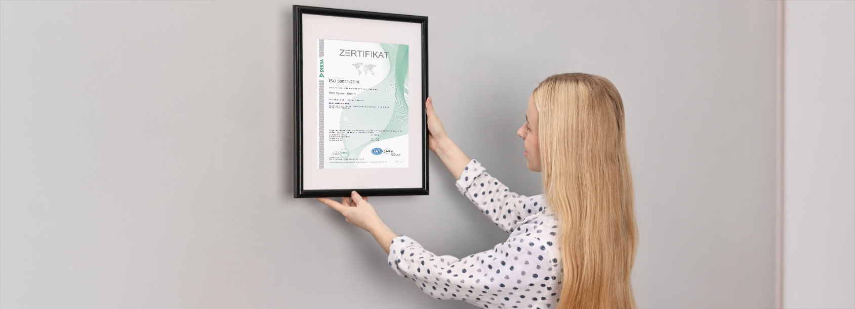 Mitarbeiterin hängt Wolf-Energiezertifikat auf